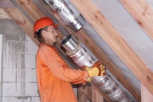 A professional installs new air ducts in an attic