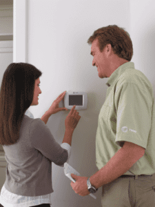 Woman adjusting thermostat while talking with man